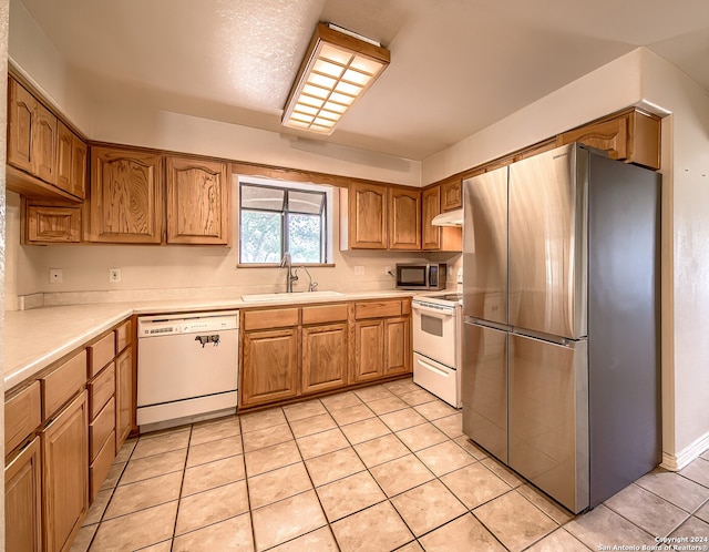 kitchen with appliances with stainless steel finishes, light tile patterned floors, and sink