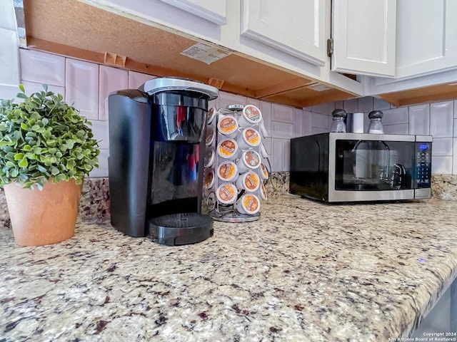 interior details with white cabinetry and light stone countertops