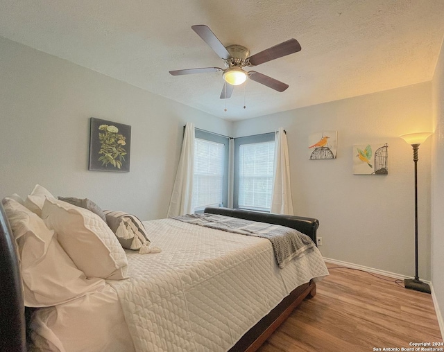 bedroom with ceiling fan, light wood-type flooring, and a textured ceiling