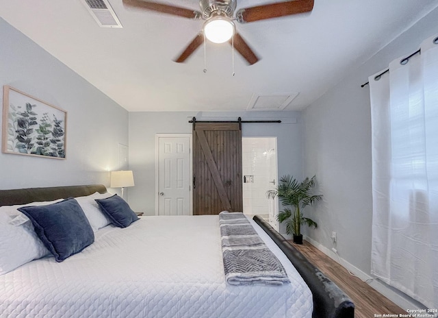 bedroom with a barn door, ceiling fan, and hardwood / wood-style floors