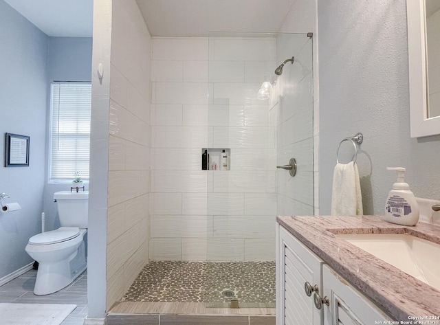 bathroom with vanity, toilet, and tiled shower