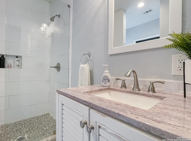 bathroom with vanity and tiled shower