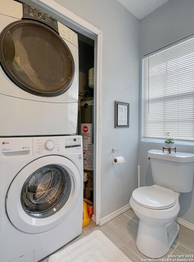 laundry area with stacked washer and clothes dryer and water heater