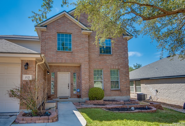 view of front of property with a garage, a front yard, and central AC unit