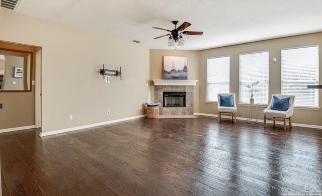 unfurnished living room featuring dark wood-type flooring, plenty of natural light, and a tiled fireplace