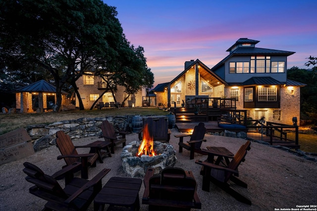 patio terrace at dusk featuring a gazebo, a fire pit, and a wooden deck