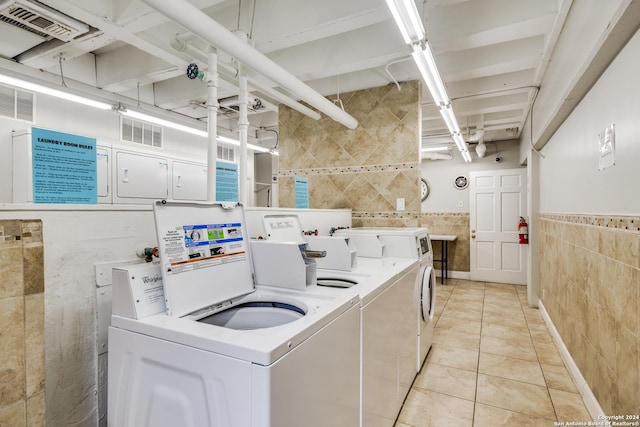 clothes washing area featuring tile walls, light tile patterned floors, and independent washer and dryer