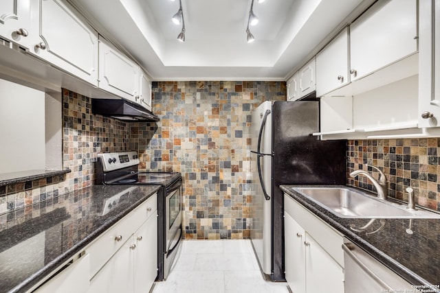 kitchen featuring stainless steel appliances, track lighting, a tray ceiling, white cabinets, and sink