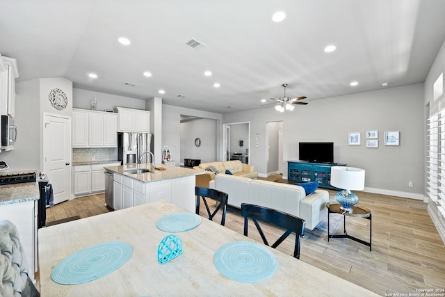 dining space with ceiling fan, sink, light hardwood / wood-style floors, and lofted ceiling