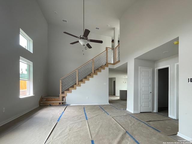 unfurnished living room with a towering ceiling and ceiling fan