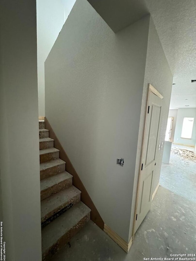 staircase featuring a textured ceiling