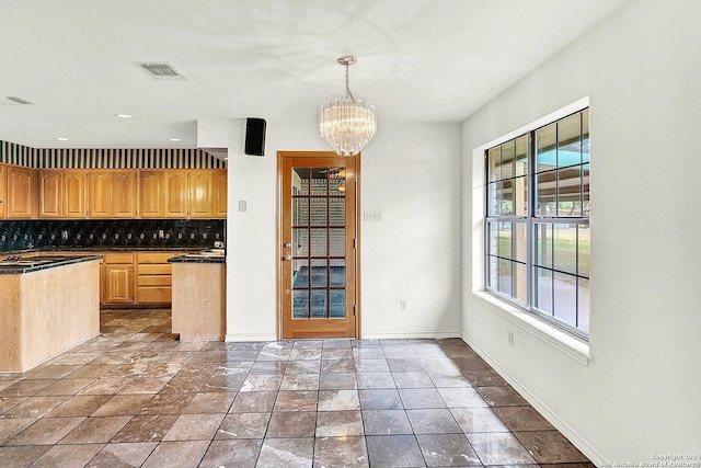 kitchen featuring backsplash, light brown cabinetry, decorative light fixtures, and an inviting chandelier