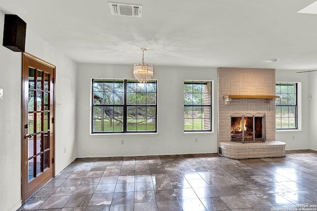 unfurnished living room featuring a fireplace and a notable chandelier