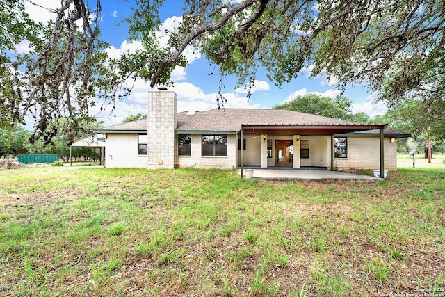 back of property with a lawn and a patio area