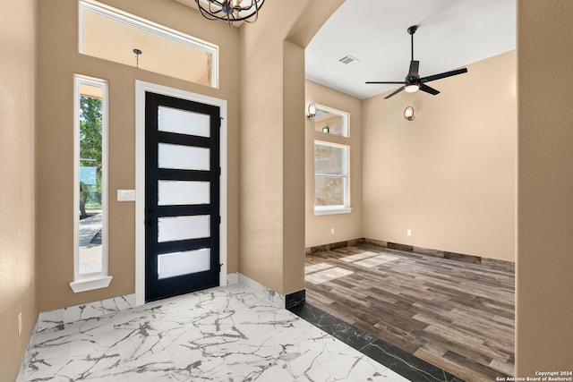 entrance foyer with hardwood / wood-style floors, ceiling fan with notable chandelier, and a wealth of natural light