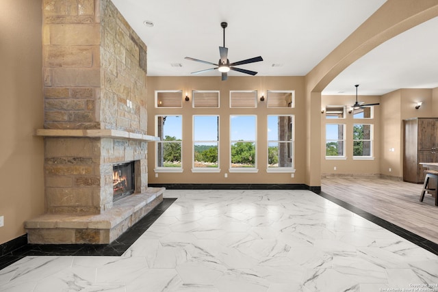 unfurnished living room with plenty of natural light, a fireplace, and ceiling fan