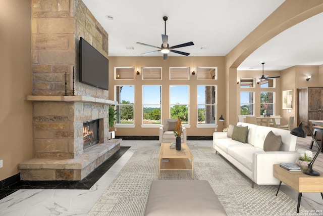 living room featuring ceiling fan and a stone fireplace