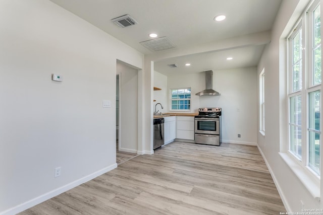 kitchen with sink, light hardwood / wood-style floors, wall chimney range hood, and appliances with stainless steel finishes