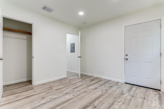 unfurnished bedroom with a closet, electric panel, and light hardwood / wood-style flooring