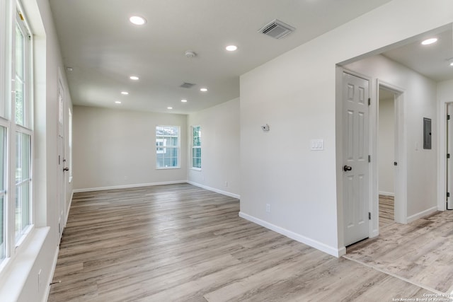 spare room with electric panel and light wood-type flooring