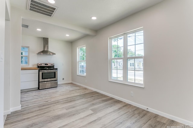 kitchen featuring wooden counters, light wood-type flooring, wall chimney exhaust hood, beamed ceiling, and stainless steel electric range