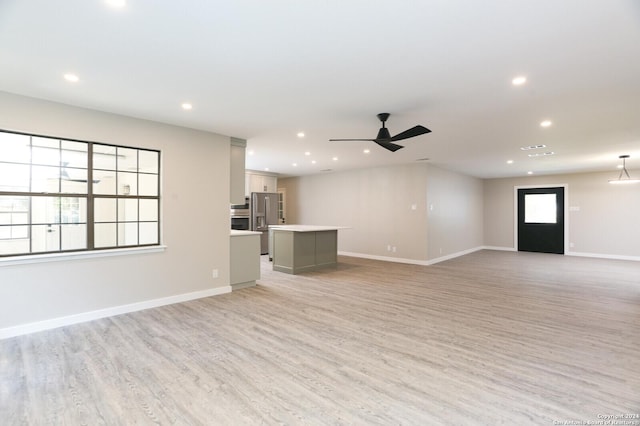 unfurnished living room featuring ceiling fan and light wood-type flooring