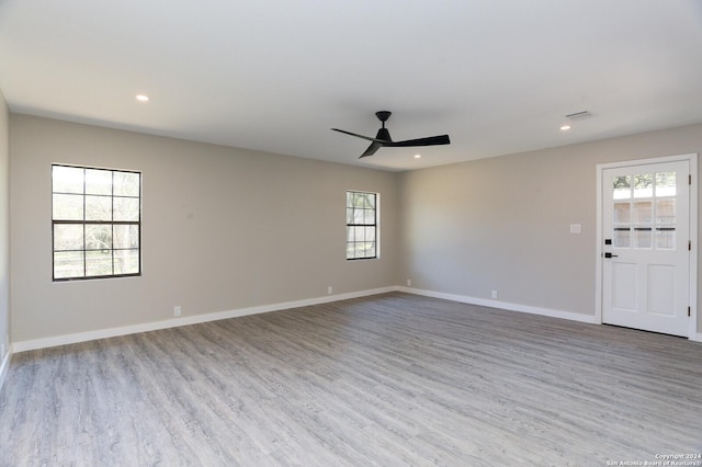 empty room featuring plenty of natural light, ceiling fan, and light wood-type flooring