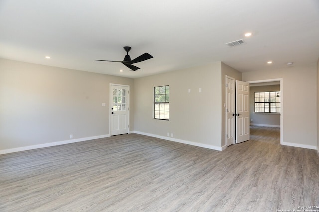 empty room with plenty of natural light, ceiling fan, and light wood-type flooring