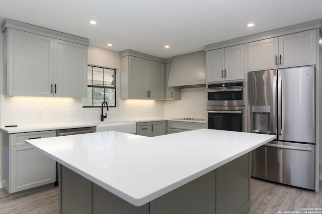 kitchen with appliances with stainless steel finishes, gray cabinets, a kitchen island, and sink