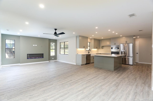 kitchen featuring ceiling fan, gray cabinets, light wood-type flooring, appliances with stainless steel finishes, and a kitchen island