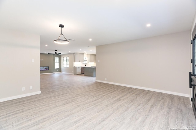 unfurnished living room with ceiling fan and light wood-type flooring