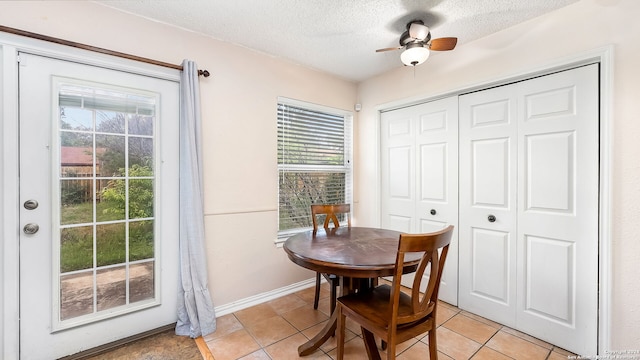 tiled dining area with ceiling fan, a wealth of natural light, and a textured ceiling