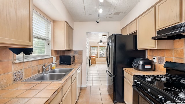 kitchen with sink, tile countertops, light tile patterned flooring, rail lighting, and black appliances