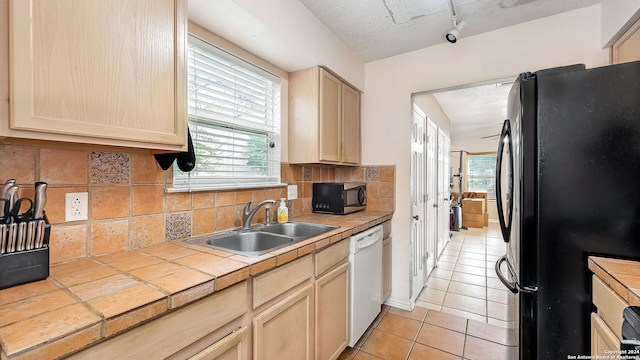 kitchen with tile countertops, light brown cabinetry, light tile patterned floors, black appliances, and sink