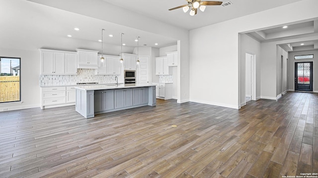 kitchen with a kitchen island with sink, plenty of natural light, white cabinets, and hardwood / wood-style flooring