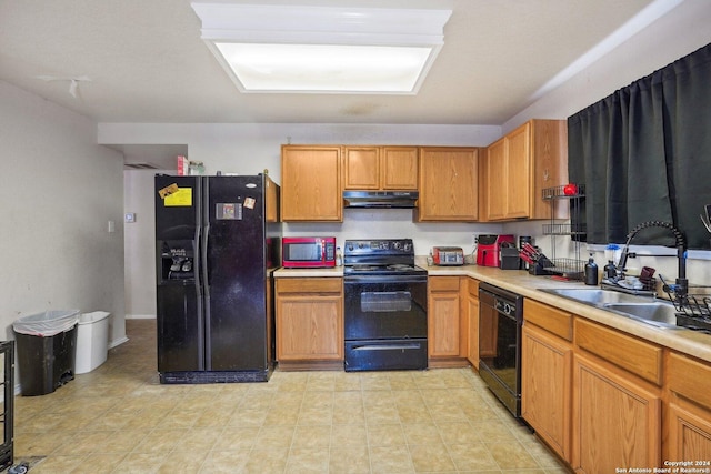 kitchen with black appliances, light countertops, under cabinet range hood, and a sink