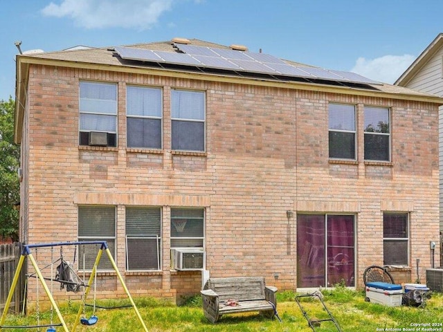 rear view of property with brick siding and solar panels