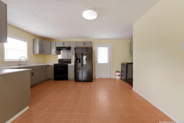 kitchen featuring washing machine and clothes dryer, sink, gray cabinets, and black appliances