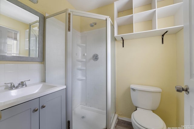 bathroom with backsplash, vanity, wood-type flooring, toilet, and a shower with shower door