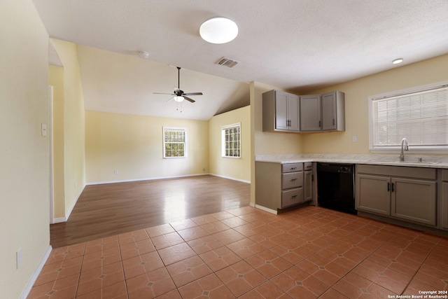 kitchen featuring ceiling fan, dishwasher, sink, wood-type flooring, and vaulted ceiling