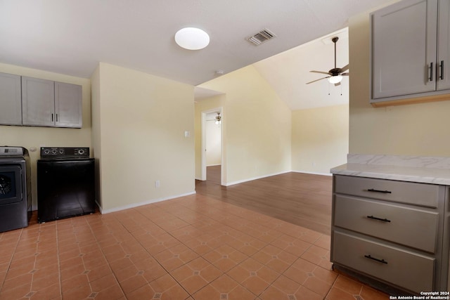 kitchen with gray cabinetry, vaulted ceiling, ceiling fan, separate washer and dryer, and light hardwood / wood-style floors