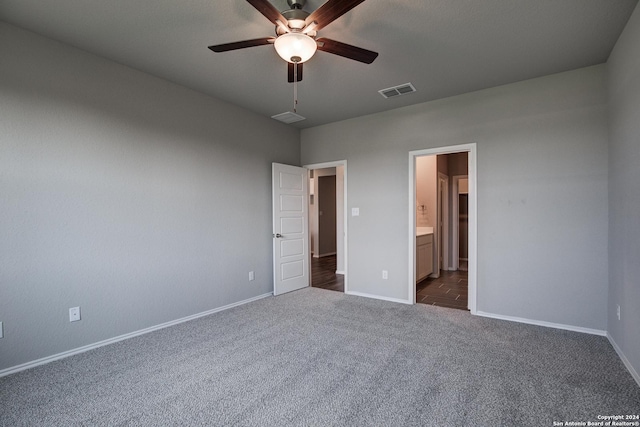 unfurnished bedroom featuring ceiling fan, ensuite bathroom, and dark colored carpet