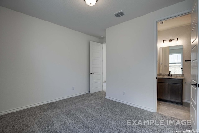 unfurnished bedroom with light colored carpet, connected bathroom, and sink