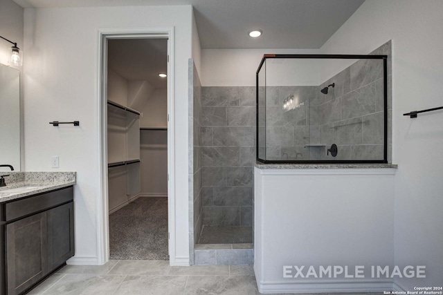 bathroom with vanity, tile patterned flooring, and a tile shower