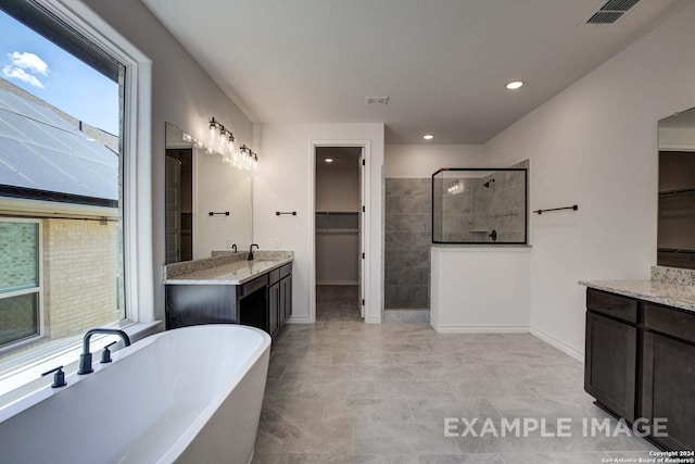 bathroom with a wealth of natural light, shower with separate bathtub, and vanity