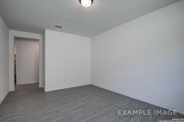 unfurnished room featuring dark wood-type flooring and a textured ceiling