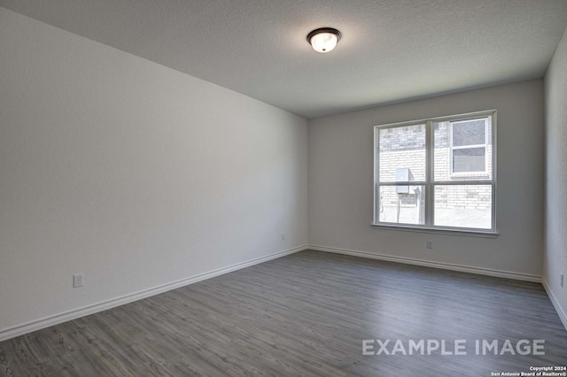 empty room featuring a textured ceiling and dark hardwood / wood-style floors