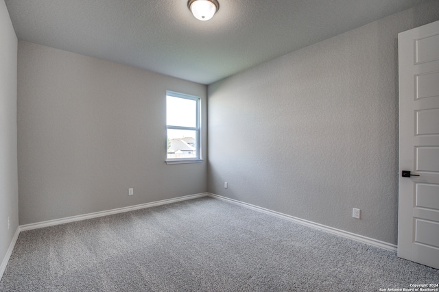 empty room with a textured ceiling and carpet flooring