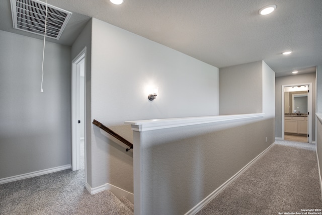 hall featuring a textured ceiling and light colored carpet