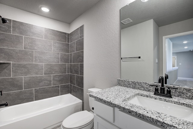 full bathroom featuring toilet, tiled shower / bath combo, vanity, and a textured ceiling